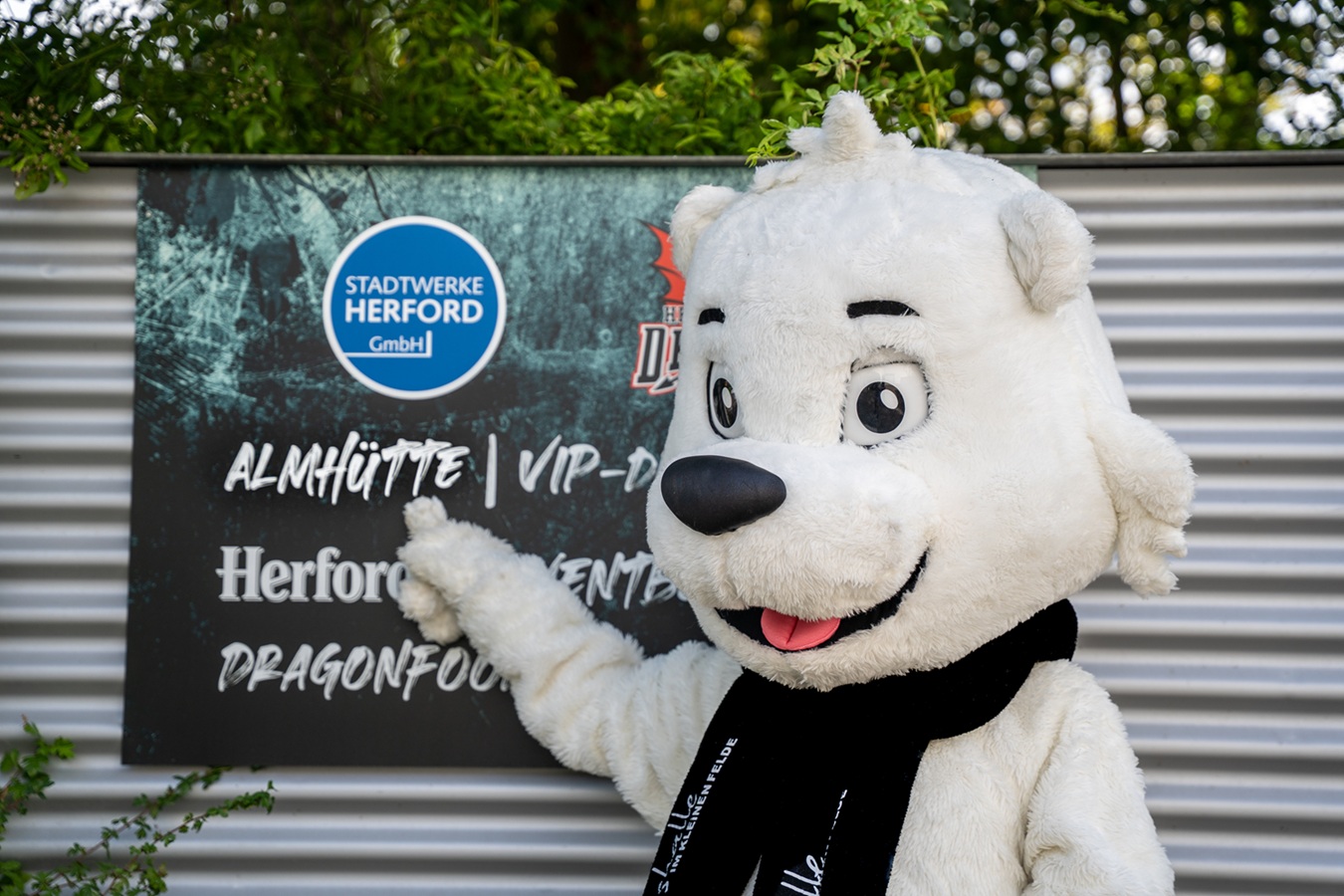 Eishalle Herford Maskotchen zeigt auf Almhütte Plakat